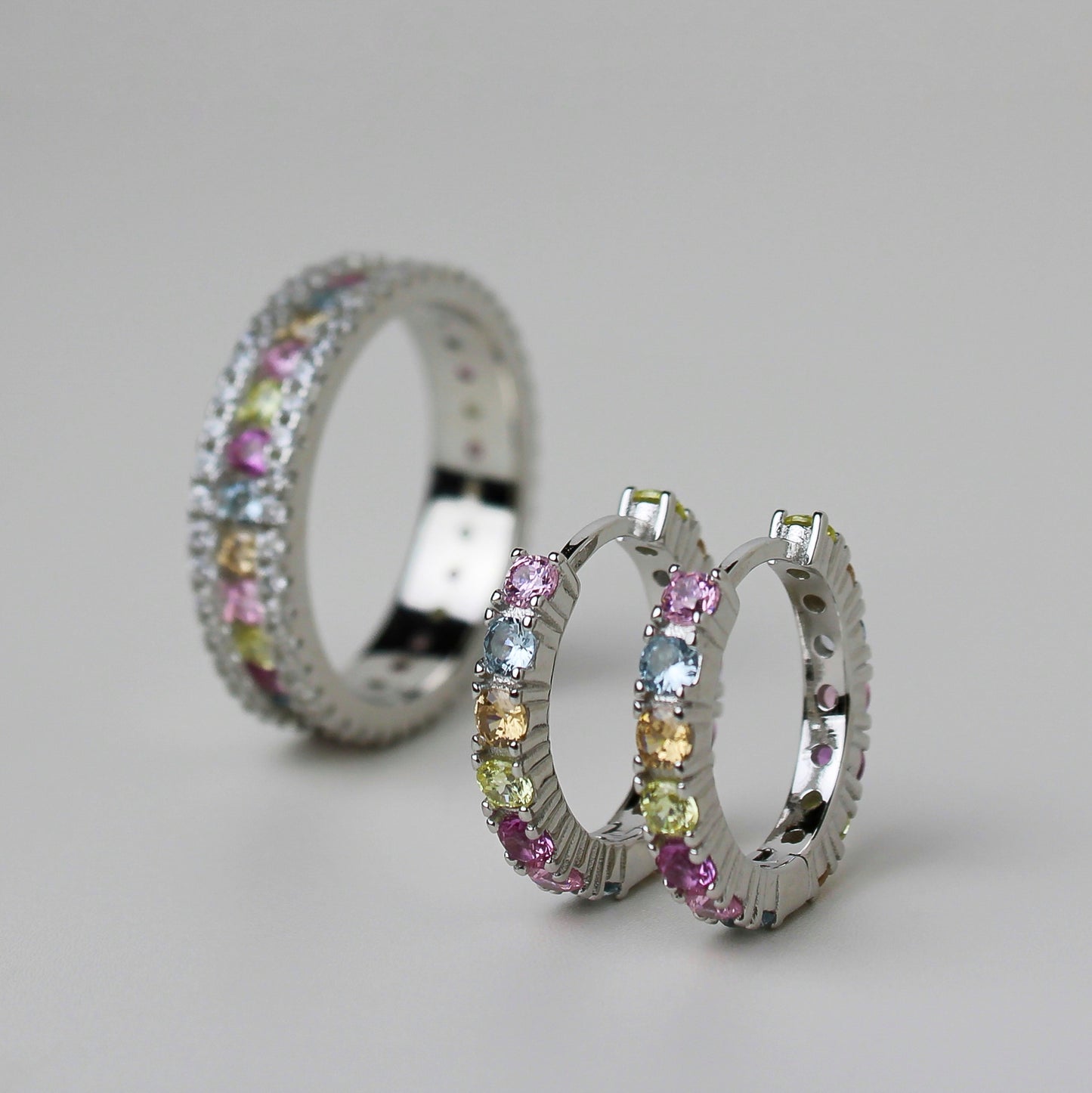 'Studded huggie hoops' with pastel colored zirconia, and 'the studded band' with pastel colored zirconia.